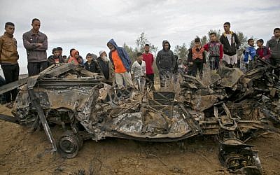Los palestinos están parados junto a los restos de un automóvil presuntamente usado por las fuerzas especiales israelíes durante una redada en Gaza, que luego fue destruido en un ataque aéreo israelí, en Khan Younis en el sur de la Franja de Gaza el 12 de noviembre de 2018. (Dijo KHATIB / AFP )