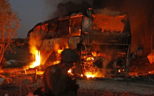 Las fuerzas de seguridad y los bomberos israelíes se reúnen cerca de un autobús incendiado luego de que un cohete disparó desde el enclave palestino, en la frontera entre Israel y Gaza cerca del kibbutz de Kfar Aza, el 12 de noviembre de 2018. (Menahem KAHANA / AFP)