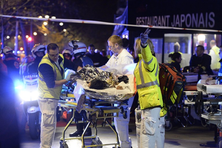 Los rescatistas evacuan a una persona lesionada cerca de la sala de conciertos de Bataclan en el centro de París, a principios del 14 de noviembre de 2015. (AFP PHOTO / MIGUEL MEDINA)