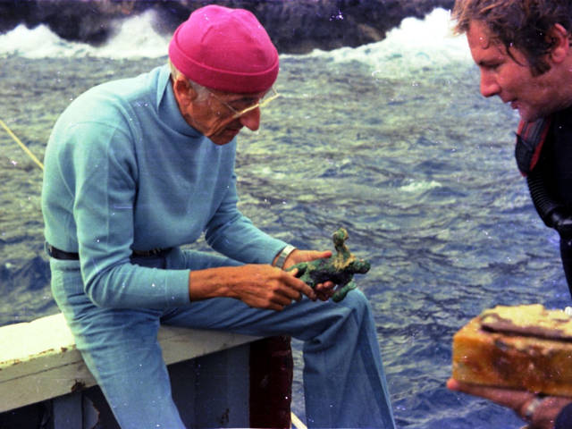 Jacques Cousteau mira una estatuilla de bronce rescatada de EUA