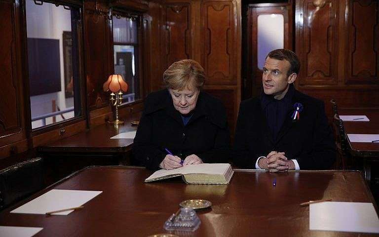 El presidente francés, Emmanuel Macron, y la canciller alemana, Angela Merkel, firman el Libro Dorado el 10 de noviembre de 2018, mientras se sientan en el vagón del tren donde se firmó el armisticio que terminó la Guerra Mundial en el claro de Rethondes (el Claro del Armisticio) en Compiegne, norte Francia. (Philippe Wojazer / Pool / AFP)