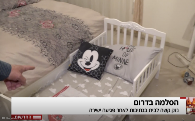El reportero de Hadashot TV Moshe Nussbaum apunta a una cuna en una habitación donde un trozo de metralla de un cohete de Hamás entró en una casa en Netivot, 12 de noviembre de 2018 (noticias de Hadashot TV)