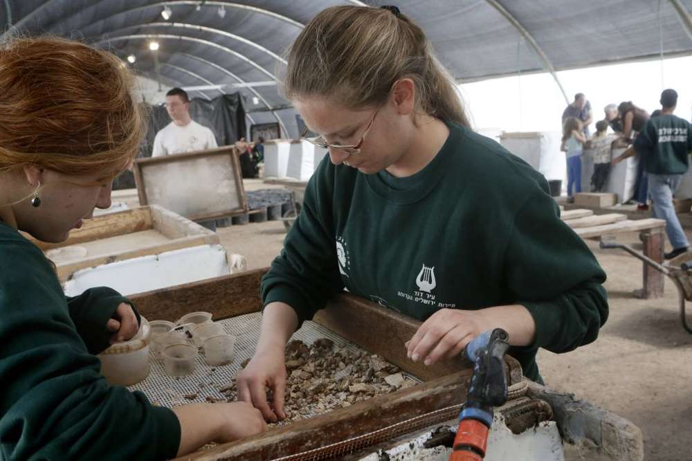 Voluntarios y empleados escogen los hallazgos en el Proyecto de Tamizado del Monte del Templo en Emek Tzurim, ubicado en el Monte de los Olivos, cerca de la Ciudad Vieja de Jerusalén el 10 de marzo de 2014. (Miriam Alster / Flash 90)