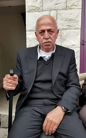 Imad Abu Asabeh sentado en la acera cerca de la Mezquita Nabi Younis en una ciudad de Cisjordania el 14 de noviembre de 2018. (Adam Rasgon / Times of Israel)