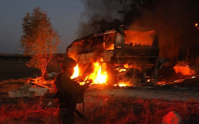 Las fuerzas de seguridad y los bomberos israelíes se reúnen cerca de un autobús incendiado después de que fue alcanzado por un misil antitanque disparado desde el enclave palestino, en la frontera entre Israel y Gaza cerca del kibbutz de Kfar Aza, el 12 de noviembre de 2018. (Foto por Menahem KAHANA / AFP)