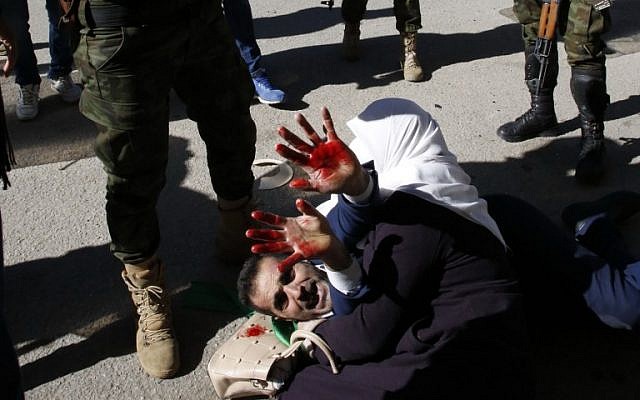 Una mujer palestina protege a su esposo herido cuando las fuerzas de seguridad palestinas intentan dispersar un mitin de simpatizantes de Hamás en Hebrón el 14 de diciembre de 2018. (Hazem Bader / AFP)