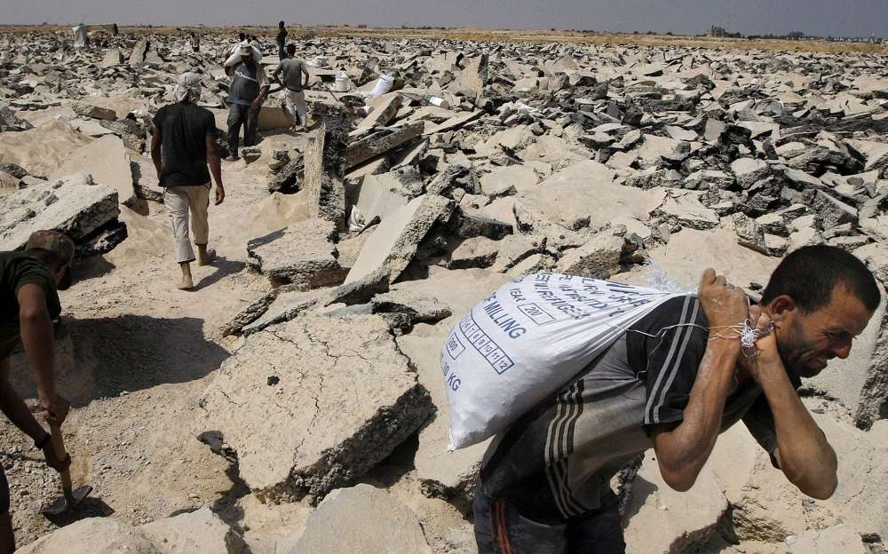 Los palestinos excavan en lo que una vez fue la pista del aeropuerto bombardeado de Gaza para recoger los escombros y la grava necesarios para la construcción en el territorio asolado por la guerra, en las afueras de Rafah, sur de la Franja de Gaza, 16 de agosto de 2010. (Foto AP / Khalil Hamra)