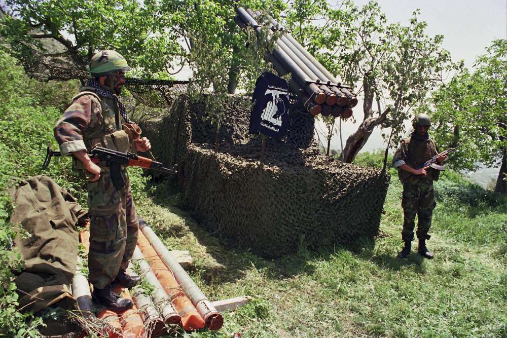 En esta foto del archivo de abril de 1996, dos combatientes de Hezbolá se colocan cerca de los cohetes Katyusha en el pueblo sureño de Ein Qana, Líbano (Foto AP / Mohammed Zaatari, archivo)