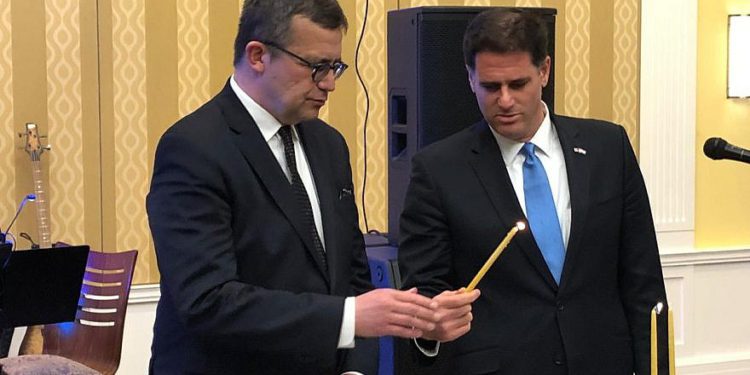 El embajador israelí en los Estados Unidos, Ron Dermer, enciende la menorá en la segunda noche de Hanukkah con la ayuda del embajador polaco en los Estados Unidos, Piotr Wilczek, en la embajada de Polonia en Washington, DC, el 3 de diciembre de 2018. Crédito: Embajador Ron Dermer /Gorjeo.