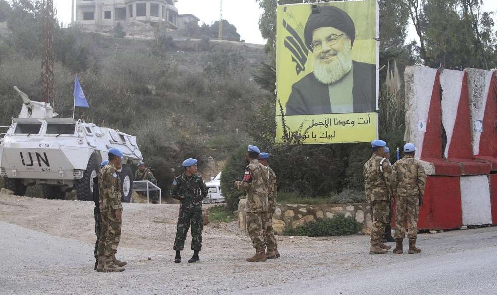 El personal de mantenimiento de la paz de la ONU de Indonesia está frente a un cartel del líder de Hezbolá, Sheikh Hassan Nasrallah, mientras patrullan el lado libanés de la frontera libanés-israelí en la aldea sur de Kfar Kila, Líbano, 4 de diciembre de 2018. (AP / Mohammed Zaatari)