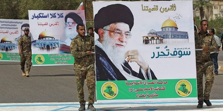 Milicianos chiítas portan un póster del líder supremo de Irán, el ayatolá Ali Khamenei, mientras pisaban un dibujo de una bandera israelí, durante un mitin del Día de Jerusalén en la capital iraquí de Bagdad el 8 de junio de 2018. (Foto de AFP / Ahmad Al-Rubaye)