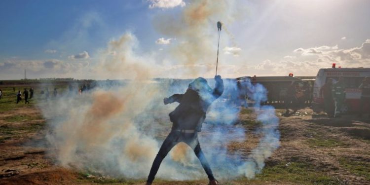 Un palestino usa una honda para lanzar gases lacrimógenos contra las fuerzas israelíes durante una manifestación en la cerca israelí al este de la ciudad de Gaza el 18 de enero de 2019. (Dijo KHATIB / AFP)