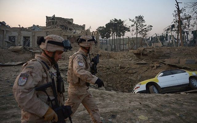 Soldados croatas de la coalición de la OTAN pasan frente a un cráter de una explosión de bomba mientras inspeccionan el sitio de un ataque al consulado alemán en Mazar-i-Sharif, Afganistán, el 11 de noviembre de 2016. (AFP / Farshad Usyan)