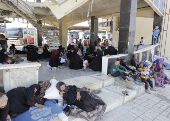 Los sirios desplazados que huyeron con sus familias en las áreas controladas por el Estado Islámico en Raqqa, Deir Ezzor y Mayadeen se reúnen en la estación de autobuses de Ramussa en Aleppo el 4 de julio de 2017. (AFP PHOTO / JOSEPH EID)