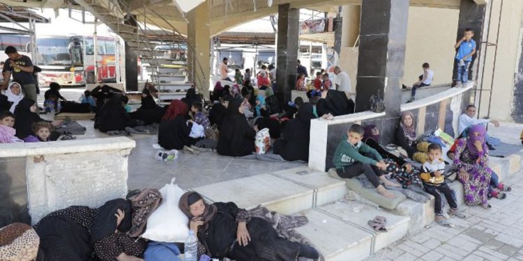 Los sirios desplazados que huyeron con sus familias en las áreas controladas por el Estado Islámico en Raqqa, Deir Ezzor y Mayadeen se reúnen en la estación de autobuses de Ramussa en Aleppo el 4 de julio de 2017. (AFP PHOTO / JOSEPH EID)