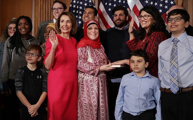 Rashida Tlaib (en thobe rojo y gafas), acompañada por su familia, jurando con la Presidenta de la Cámara de Representantes Nancy Pelosi (con vestido rosa), en el Capitolio de los Estados Unidos en Washington, DC, 3 de enero de 2019. (Chip Somodevilla / Getty Imágenes / AFP)