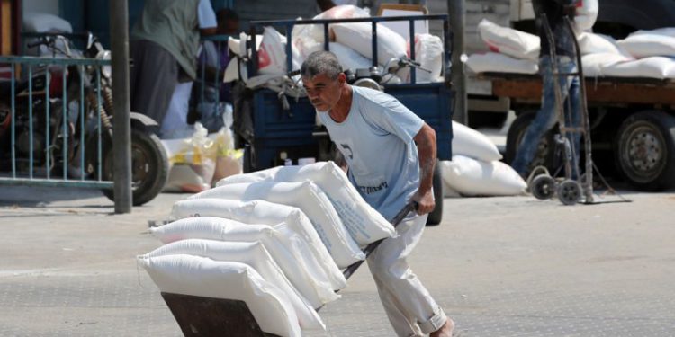 Un palestino empuja un carrito con bolsas de harina en un centro de distribución de ayuda administrado por el Organismo de Obras Públicas y Socorro de las Naciones Unidas (UNRWA) en Khan Younis, en el sur de la Franja de Gaza, 1 de septiembre de 2018 .. (crédito de foto: REUTERS / IBRAHEEM ABU MUSTAFA)