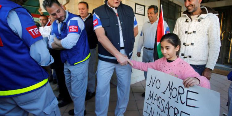 Una niña palestina le da la mano a un miembro de la Presencia Internacional Temporal en Hebrón (TIPH) durante una protesta contra la decisión del Primer Ministro israelí, Benjamin Netanyahu, de no renovar el mandato de TIPH, en Hebrón, el 30 de enero de 2019. Mussa Qawasma / Reuters