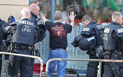 En esta foto del 6 de octubre de 2018, los oficiales de policía buscan a un visitante de un concierto de rock neo-nazi en Aploda, Alemania. El eslogan en la camiseta dice "garantizado indexado". (Sebastian Haak / dpa via AP)