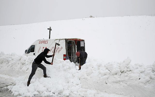 Dos sirios quitan la nieve, para abrir un camino a su camioneta donde venden bebidas calientes, en el costado de una carretera en el pueblo de Mdeirij, en el Monte Líbano, el 9 de enero de 2019. (Foto AP / Bilal Hussein)