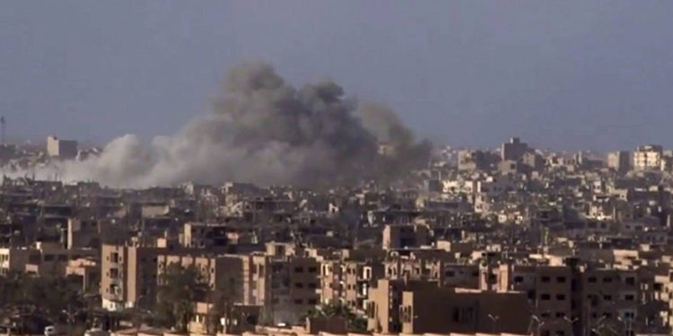 Archivo: Humo y escombros en aumento después del bombardeo del gobierno sirio de la ciudad de Deir el-Zour durante una batalla contra el Estado Islámico en 2017 (SANA a través de AP)