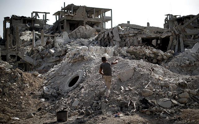 Un joven camina a través de los escombros en el campamento de refugiados palestinos de Yarmouk, en la capital siria, Damasco, Siria, 6 de octubre de 2018 (AP Photo / Hassan Ammar)