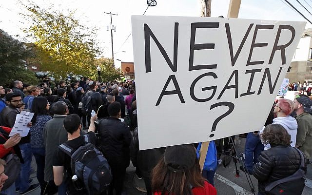 Una persona sostiene un cartel durante una reunión de protesta en el bloque del Centro Comunitario Judío en el vecindario de Squirrel Hill en Pittsburgh, donde se realizó el funeral del Dr. Jerry Rabinowitz, el martes 30 de octubre de 2018. (AP / Gene J. Puskar)