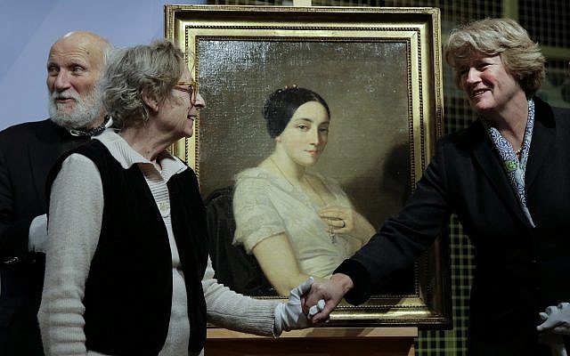 Monika Gruetters, Comisionada del Gobierno para los Medios y la Cultura, derecha, comprende la pintura "Retrato de una joven sentada" de Thomas Couture a Franz Rainer Wolfgang Joachim Kleinertz, izquierda, y María de las Mercedes Estrada, segunda a la izquierda, herederos del judío francés el político Georges Mandel, durante una ceremonia de restitución en Berlín, el 8 de enero de 2019. (AP Photo / Markus Schreiber)