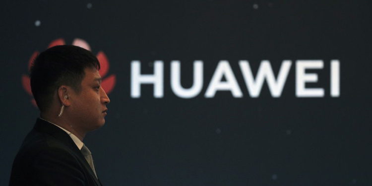 En esta foto del 9 de enero de 2019, un guardia de seguridad se encuentra cerca del logotipo de la compañía Huawei durante un evento de lanzamiento de un nuevo producto en Beijing (AP Photo / Andy Wong)