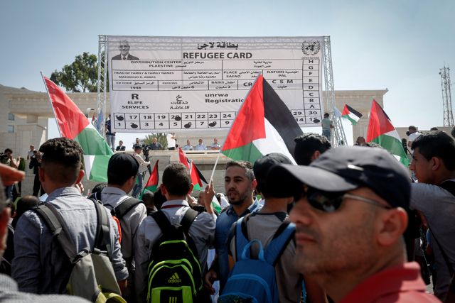 Los manifestantes palestinos agitan su bandera nacional frente a una tarjeta de refugiado gigante fabricada durante una protesta contra la decisión de Estados Unidos de recortar los fondos de la ONU a los palestinos en la ciudad de Belén, Cisjordania, el 26 de septiembre de 2018. Crédito: Wisam Hashlamoun / Flash90.