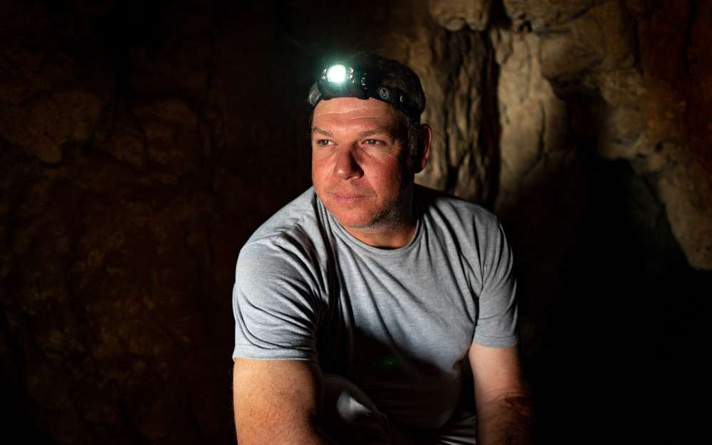 Investigador Oren Gutfeld dentro de la Cueva 52 en el sitio arqueológico de Qumran, 22 de enero de 2019. (Luke Tress / Times of Israel)