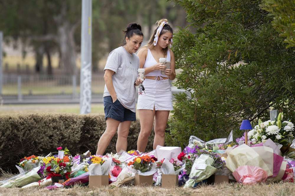 Dos mujeres están en un tributo floral, el viernes 18 de enero de 2019, en la escena donde el cuerpo de la estudiante israelí Aiia Maasarwe se encontró a principios de la semana en Melbourne, Australia. (Ellen Smith / AAP Imagen a través de AP)