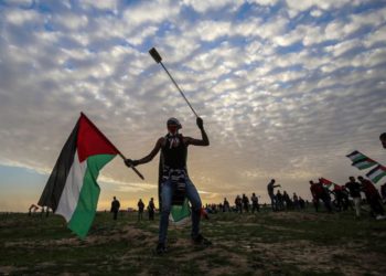 Un manifestante palestino porta una bandera nacional y una honda durante una manifestación cerca de la cerca a lo largo de la frontera con Israel, al este de la ciudad de Gaza, el 1 de febrero de 2019. (Dijo KHATIB / AFP)