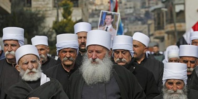 Los residentes drusos de los Altos del Golán llevan un retrato del presidente sirio Bashar al-Assad durante un mitin en la aldea de Majdal Shams el 14 de febrero de 2019 (JALAA MAREY / AFP)