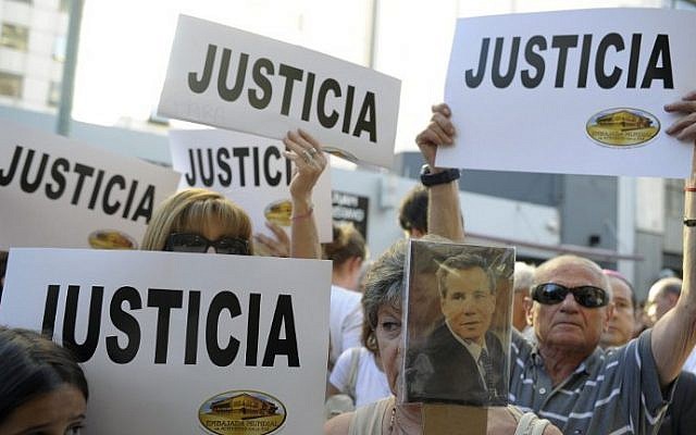 La gente sostiene pancartas que decían "Justicia" durante un mitin frente a la sede de la Asociación Mutual de Israelitas (AMIA) en Buenos Aires, el 21 de enero de 2015. (Crédito de la foto: Alejandro Pagni / AFP).