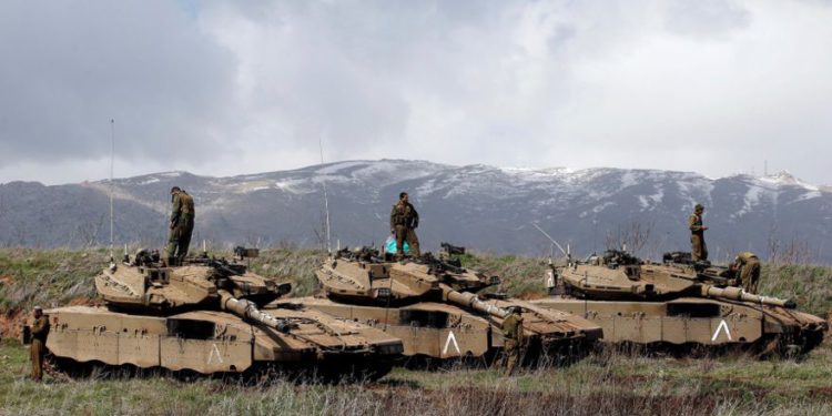 Los soldados israelíes están parados sobre tanques con vistas a la frontera entre Israel y Siria. (Crédito de la foto: RONEN ZVULUN / REUTERS)