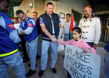 Una niña palestina le da la mano a un miembro de la Presencia Internacional Temporal en Hebrón (TIPH) en el lado palestino H1 de la ciudad durante una protesta contra la decisión de Israel de no renovar su mandato, 30 de enero de 2019. (Crédito de la foto: MUSSA QAWASMA / REUTERS)