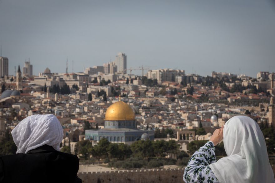 Los turistas miran una vista de la Cúpula de la Roca y el Monte del Templo desde el mirador del Monte de los Olivos que domina la ciudad vieja de Jerusalén, el 28 de noviembre de 2018. (Yonatan Sindel / Flash90)