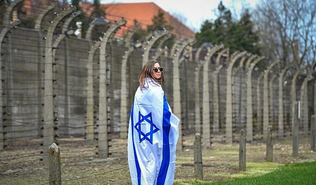 Una mujer envuelta en una bandera israelí en la Marcha de los Vivos en el campamento de Auschwitz-Birkenau en Polonia, 11 de abril de 2018 (Yossi Zeliger / Flash 90)