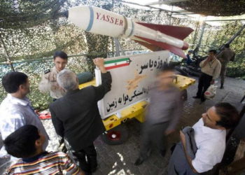 Un miembro del ejército iraní habla con un visitante mientras están parados junto a la bomba balística iraní, Yasser, durante una exhibición de guerra para conmemorar el aniversario de la guerra Irán-Irak (1980-88), en la plaza Baharestan, cerca del edificio del Parlamento en el sur de Teherán. (Crédito de la foto: REUTERS / MORTEZA NIKOUBAZL)