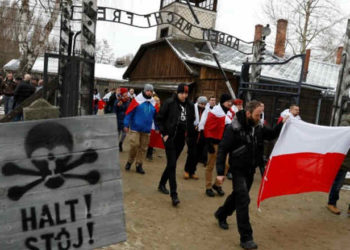 Los activistas de la derecha (ONR) (Campamento Radical Nacional) de extrema derecha pasan por la puerta "Arbeit Macht Frei" en el antiguo campo de concentración y exterminio alemán nazis Auschwitz, para rendir homenaje a las víctimas polacas en el "muro de la muerte", durante las ceremonias del 74 aniversario de la liberación del campamento y el Día Internacional de Recordación de Víctimas del Holocausto, en Oswiecim, Polonia, 27 de enero de 2019. REUTERS / Kacper Pempel.