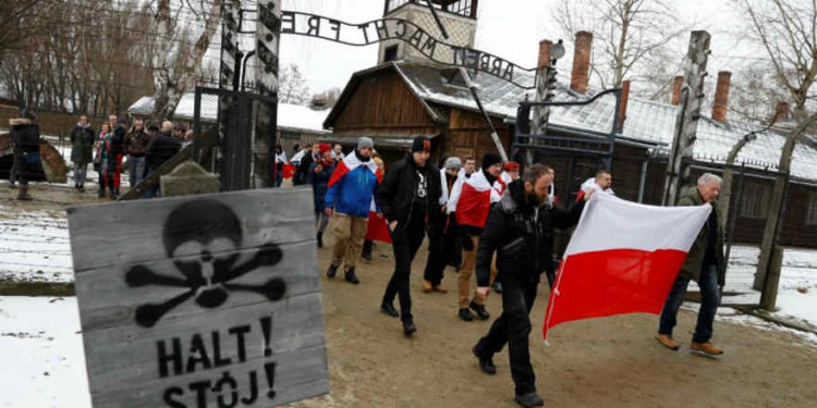 Los activistas de la derecha (ONR) (Campamento Radical Nacional) de extrema derecha pasan por la puerta "Arbeit Macht Frei" en el antiguo campo de concentración y exterminio alemán nazis Auschwitz, para rendir homenaje a las víctimas polacas en el "muro de la muerte", durante las ceremonias del 74 aniversario de la liberación del campamento y el Día Internacional de Recordación de Víctimas del Holocausto, en Oswiecim, Polonia, 27 de enero de 2019. REUTERS / Kacper Pempel.