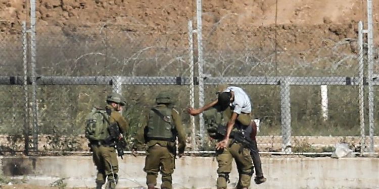 Ilustrativo: los soldados israelíes se llevan a un palestino herido que, según el ejército, intentó romper la cerca fronteriza al este de Jabaliya en el norte de la Franja de Gaza el 27 de junio de 2018. (Said Khatib / AFP)