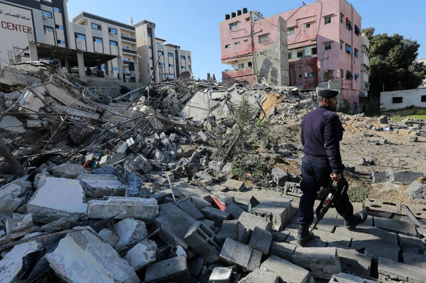 Una fotografía tomada el 26 de marzo de 2019, muestra a un policía de Hamás haciendo guardia junto a los escombros de un edificio en la ciudad de Gaza que fue atacado la noche anterior por un ataque aéreo israelí. (Mahmud Hams / AFP)