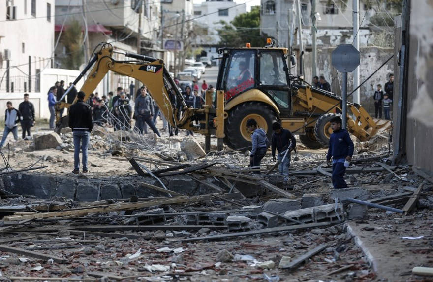 Una fotografía tomada el 26 de marzo de 2019 muestra a una excavadora limpiando escombros junto a la oficina destruida del líder de Hamás, Ismail Haniyeh, en la ciudad de Gaza, que fue atacada la noche anterior por un ataque aéreo israelí. (Mahmud Hams / AFP)