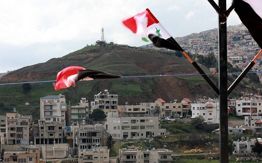 Las banderas sirias vuelan en la ciudad siria de Ain al-Tineh frente a Majdal Shams en los Altos del Golán israelíes el 26 de marzo de 2019. (Louai Beshara / AFP)