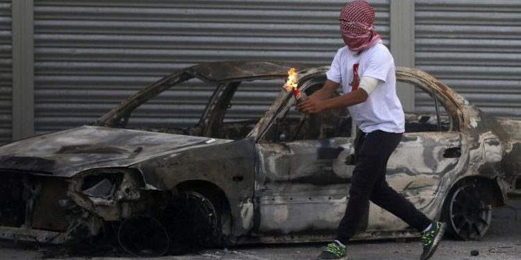 Un terrorista palestino se prepara para lanzar una bomba incendiaria durante los ataques a las fuerzas de seguridad israelíes en el campamento de refugiados de Shuafat en Jerusalem, el 9 de octubre de 2015. (Ahmad Gharabli / AFP)