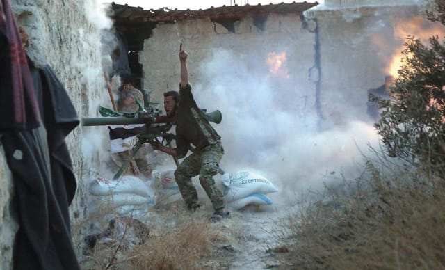 Un luchador rebelde hace un gesto mientras dispara su arma durante los enfrentamientos con las fuerzas leales al presidente de Siria, Bashar al-Assad, en la primera línea del barrio de Sheikh Saeed de Alepo, 23 de mayo de 2015 - REUTERS / Hosam Katan