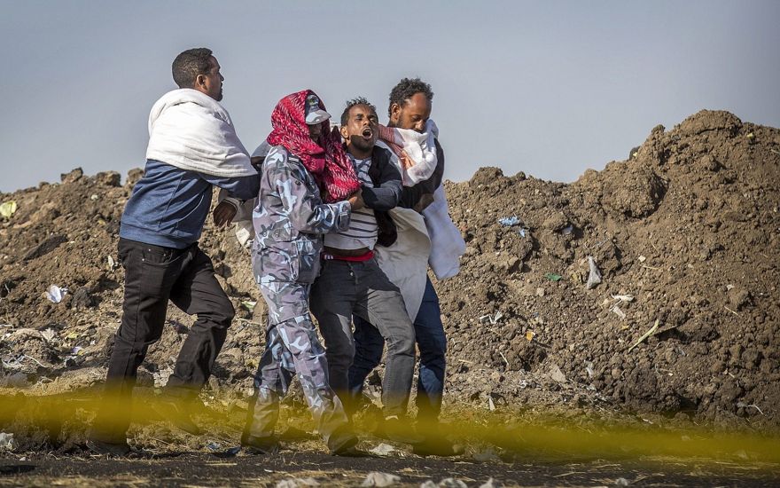Un familiar afligido que perdió a su esposa en el accidente recibe ayuda de un miembro de las fuerzas de seguridad y otros en el lugar del accidente del Boeing 737 de Ethiopian Airlines, 8 de marzo de 2019. (AP / Mulugeta Ayene)