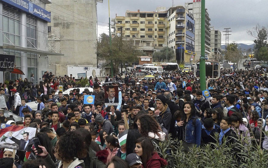 En esta foto publicada por la agencia oficial de noticias siria SANA, los sirios retratan al presidente sirio Bashar Assad durante una protesta contra el movimiento del presidente estadounidense Donald Trump para reconocer la soberanía israelí sobre los Altos del Golán, en la provincia sureña de Sweida, Siria, en marzo 26, 2019. (SANA vía AP)